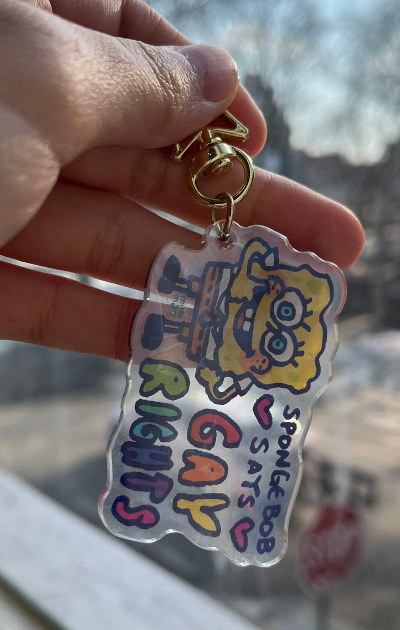 Hand holding a keychain against a blurred outdoor background.