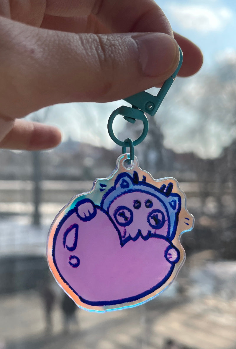 Hand holding a colorful sticker with a character design against a blurred outdoor background