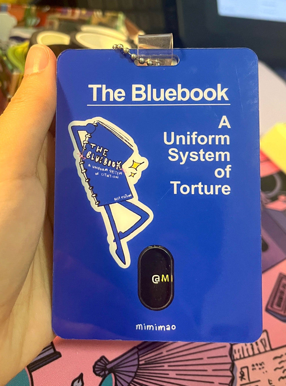 Blue card with 'The Bluebook' design and text held by a hand.
