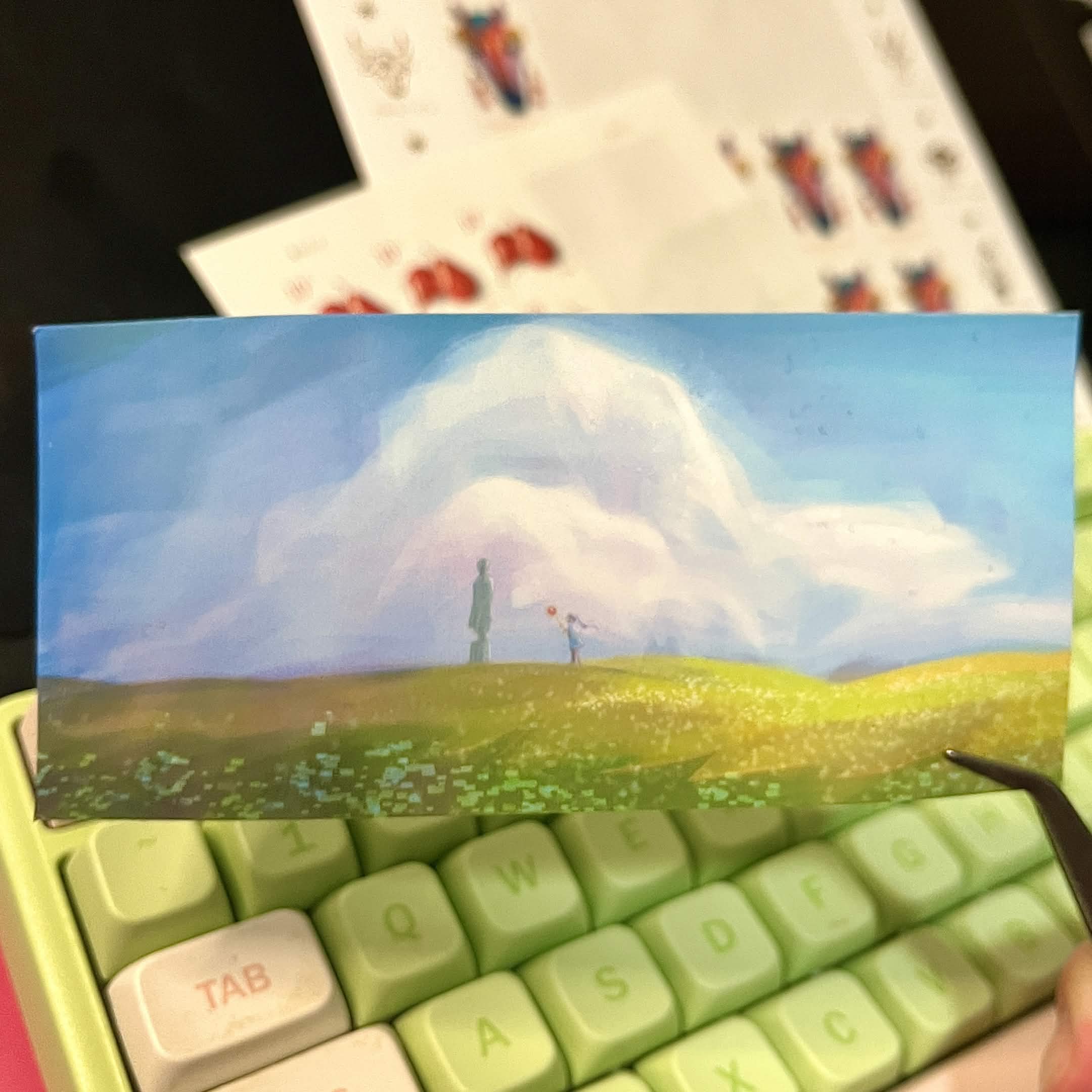 Card with a scenic design held over a green keyboard
